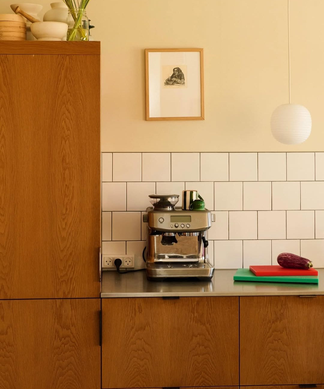 Coffee machine on a kitchen counter with wooden cabinets and a tiled wall.