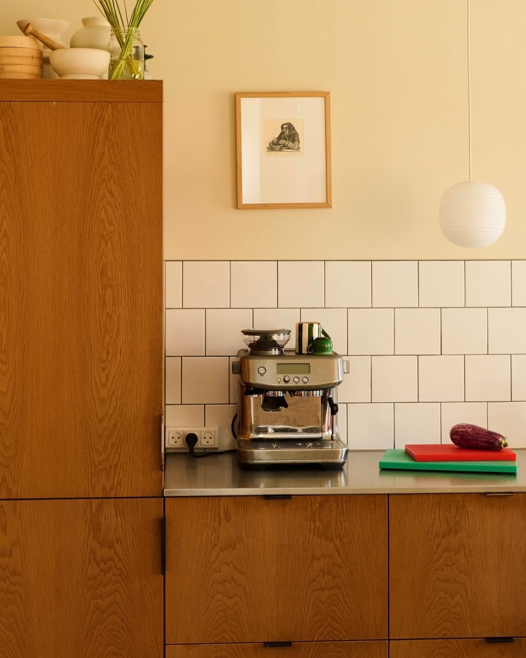 Coffee machine on a kitchen counter with wooden cabinets and a tiled wall.