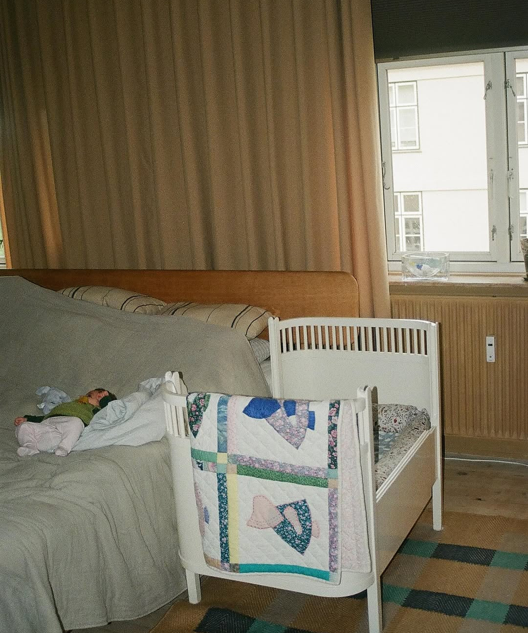 Bedroom with a bed and crib next to a window