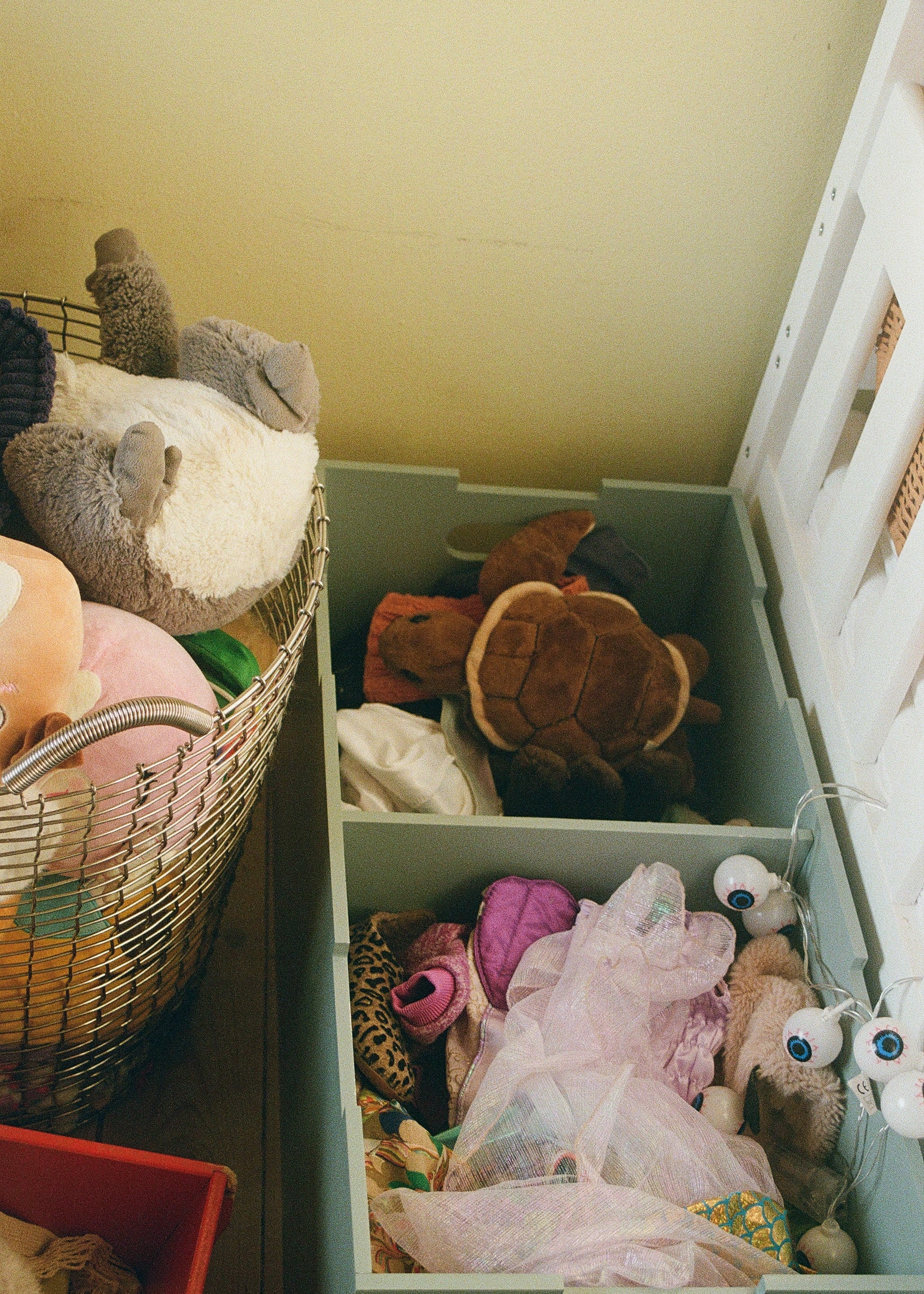 Open drawer filled with various stuffed toys and items on a yellow wall background