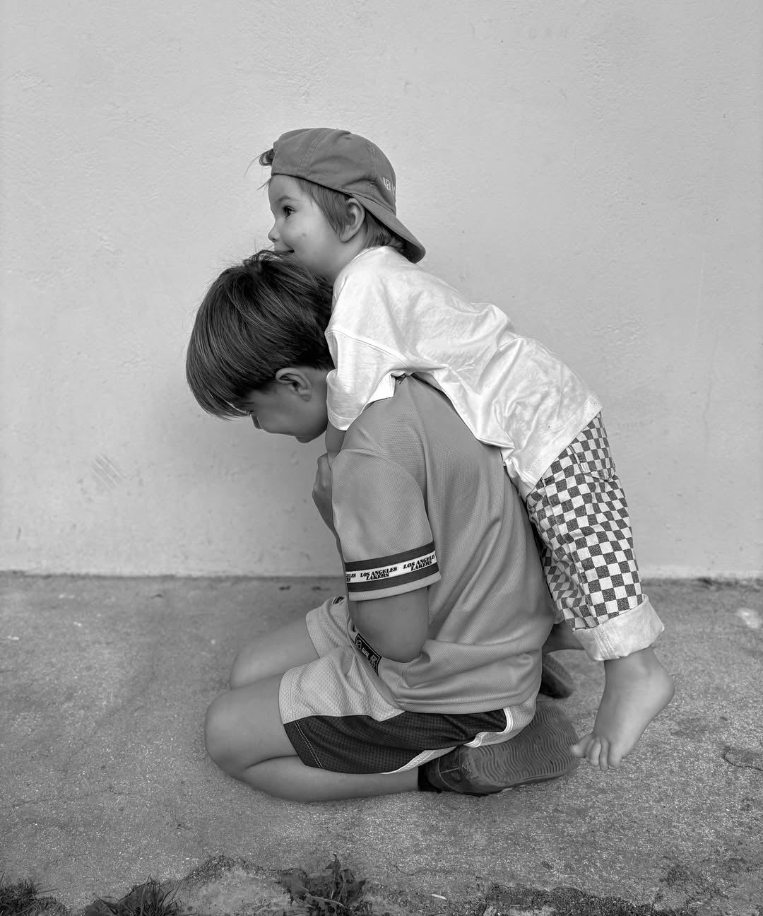 Two children playing on a concrete surface with a plain background