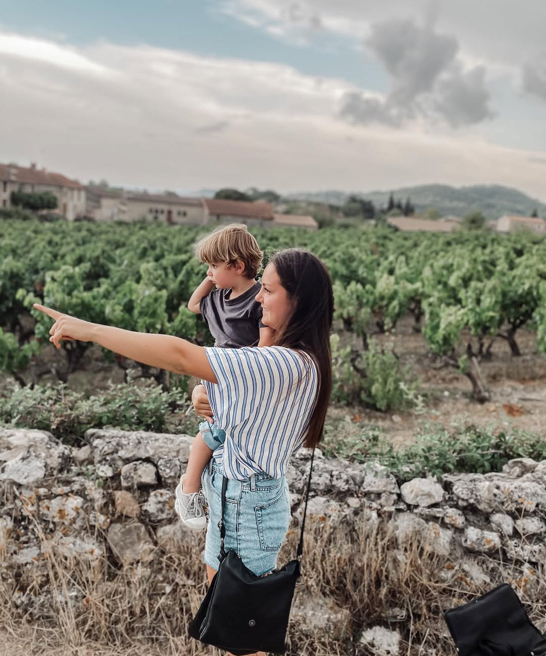 Woman with two children in a vineyard pointing towards the horizon