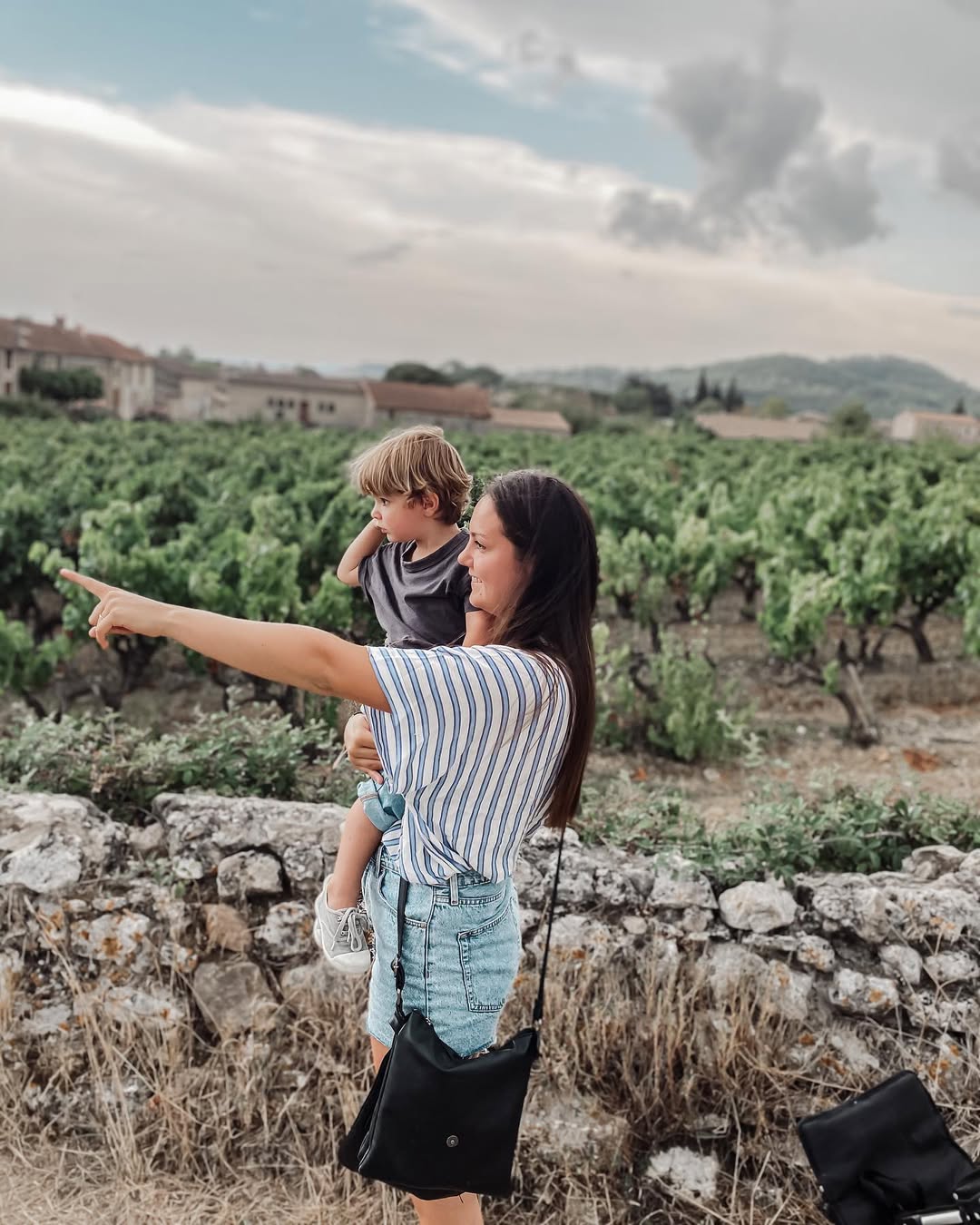 Woman with two children in a vineyard pointing towards the horizon
