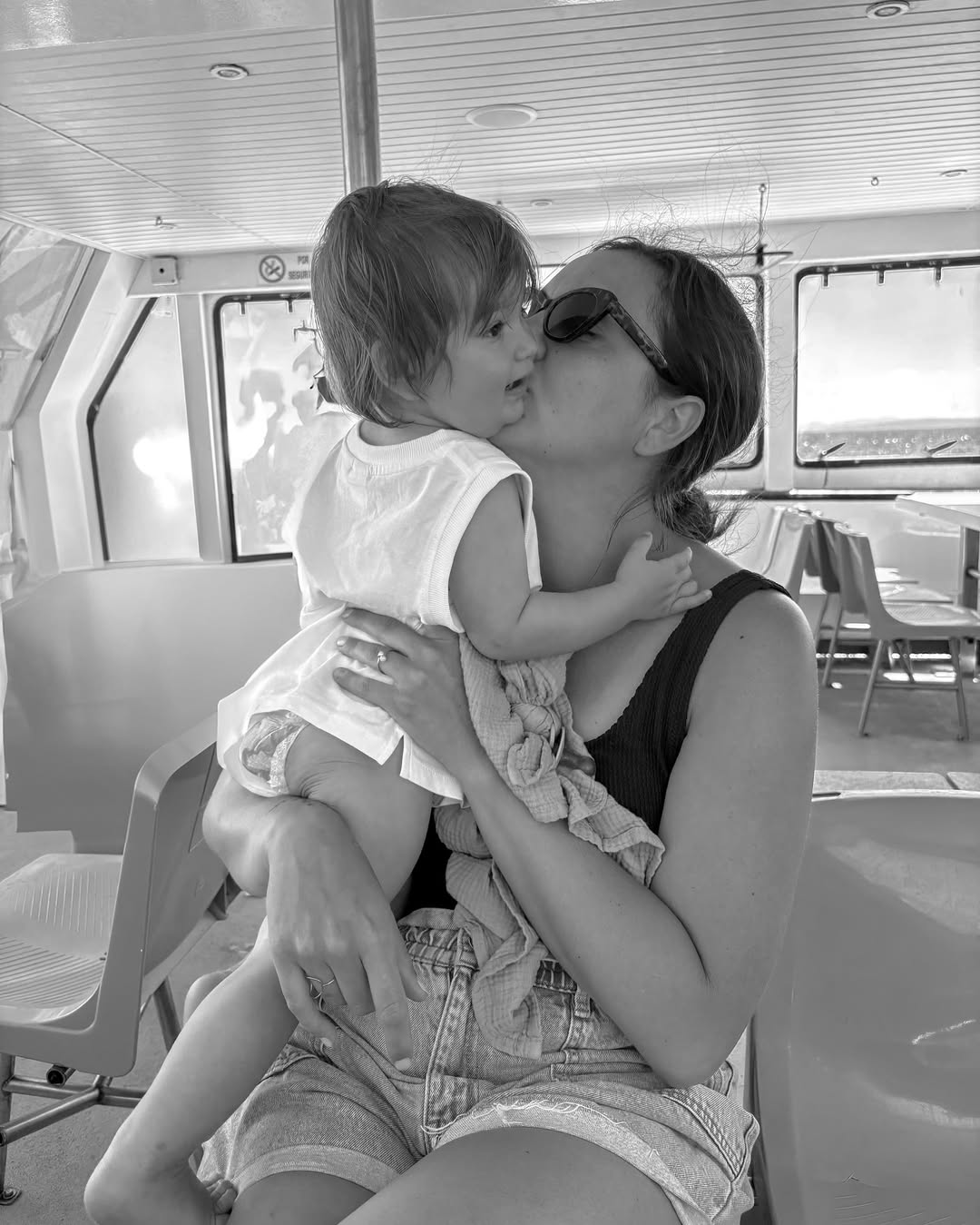 Black and white photo of a woman holding a child on a boat.