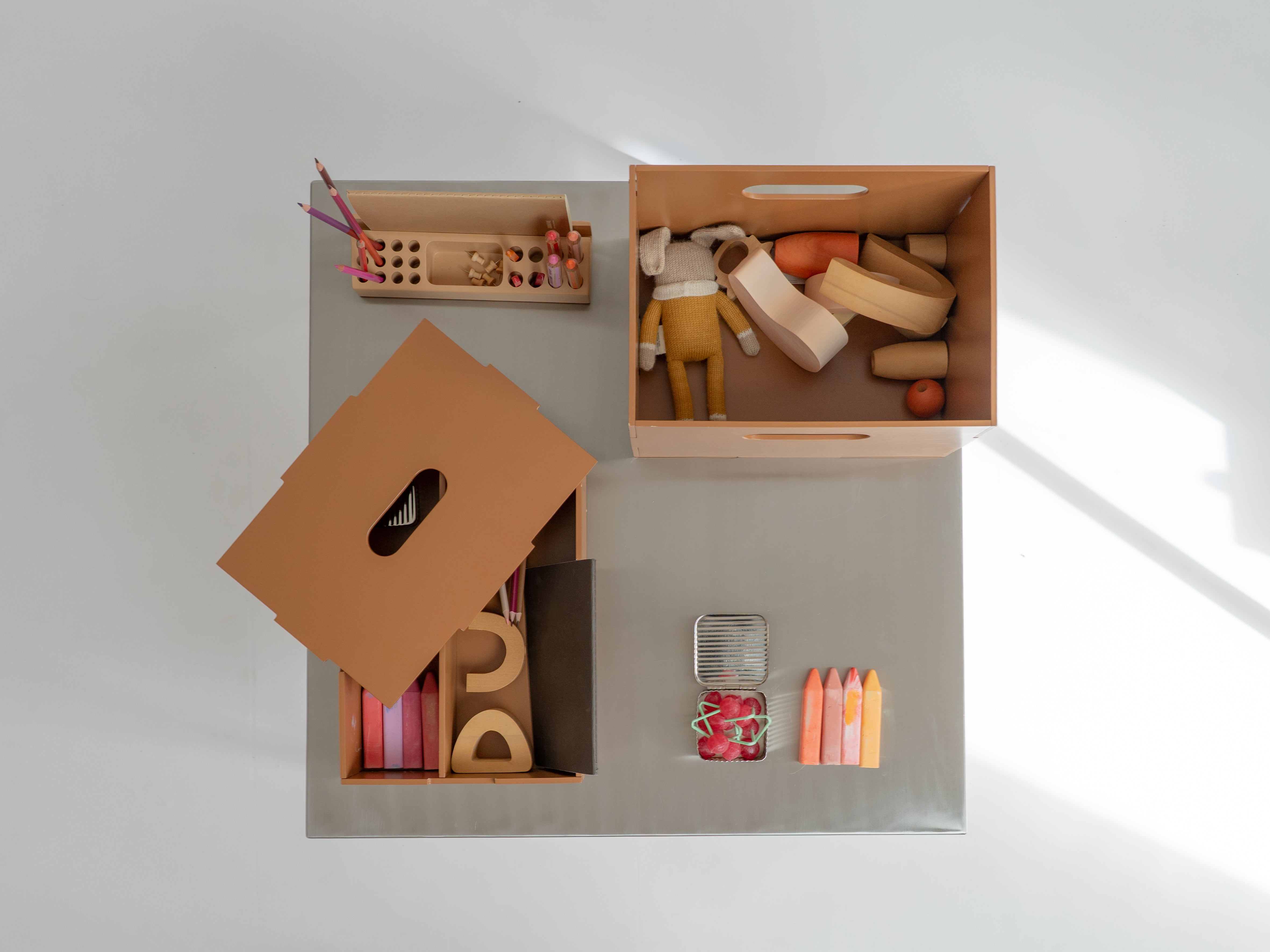 Wooden toys and educational items in open boxes on a light gray surface.