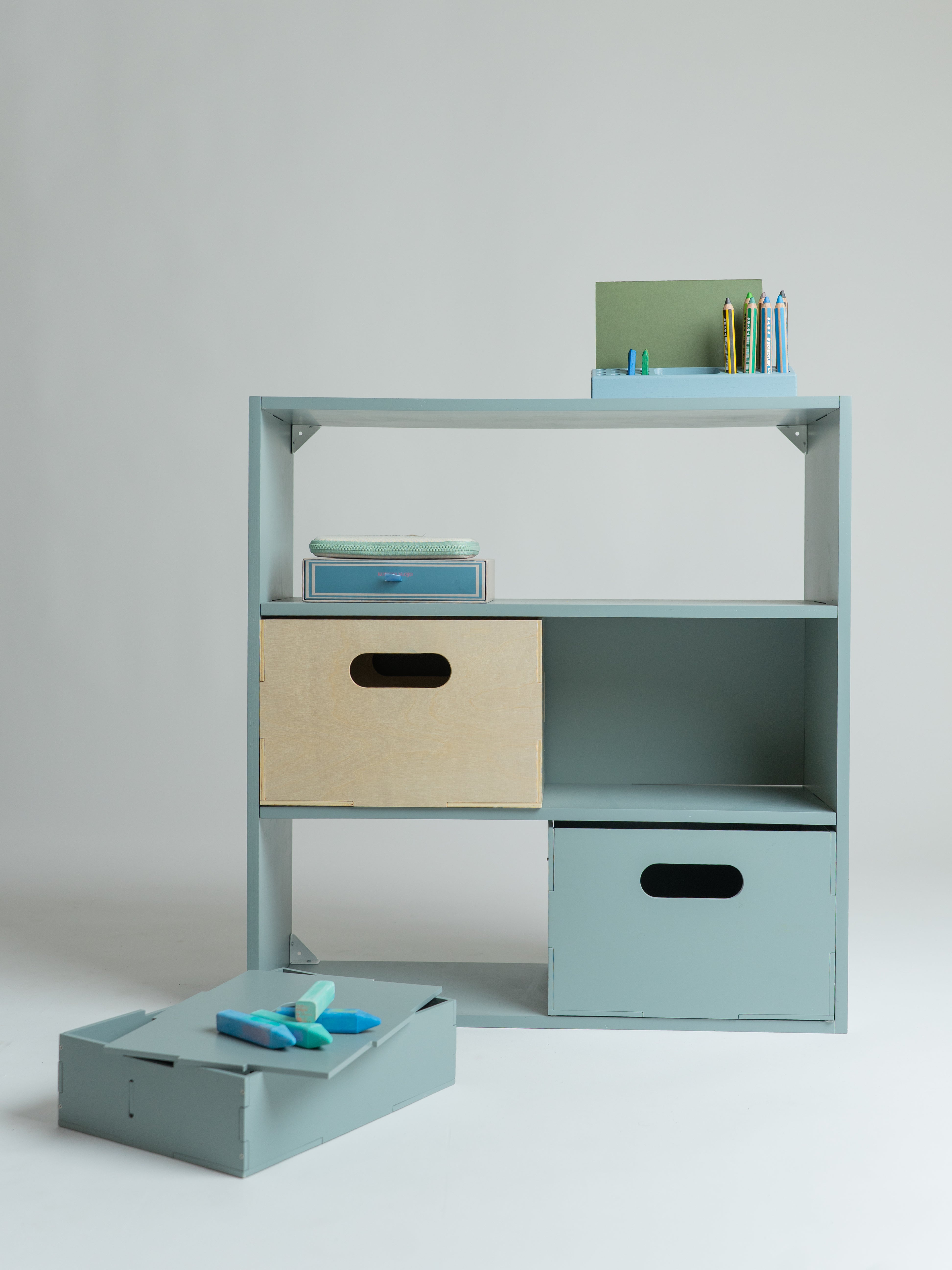 Light blue storage shelf with drawers and a small table on a plain background