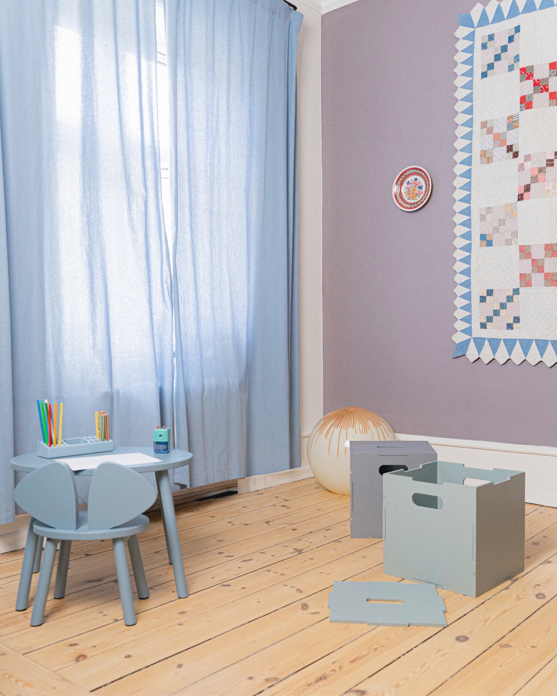Children's room with light blue furniture, wooden floor, and decorative elements.