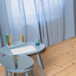 Children's table and chair set with stationery against a light curtain background