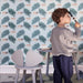 Boy stands in the children's room with wallpaper on the wall