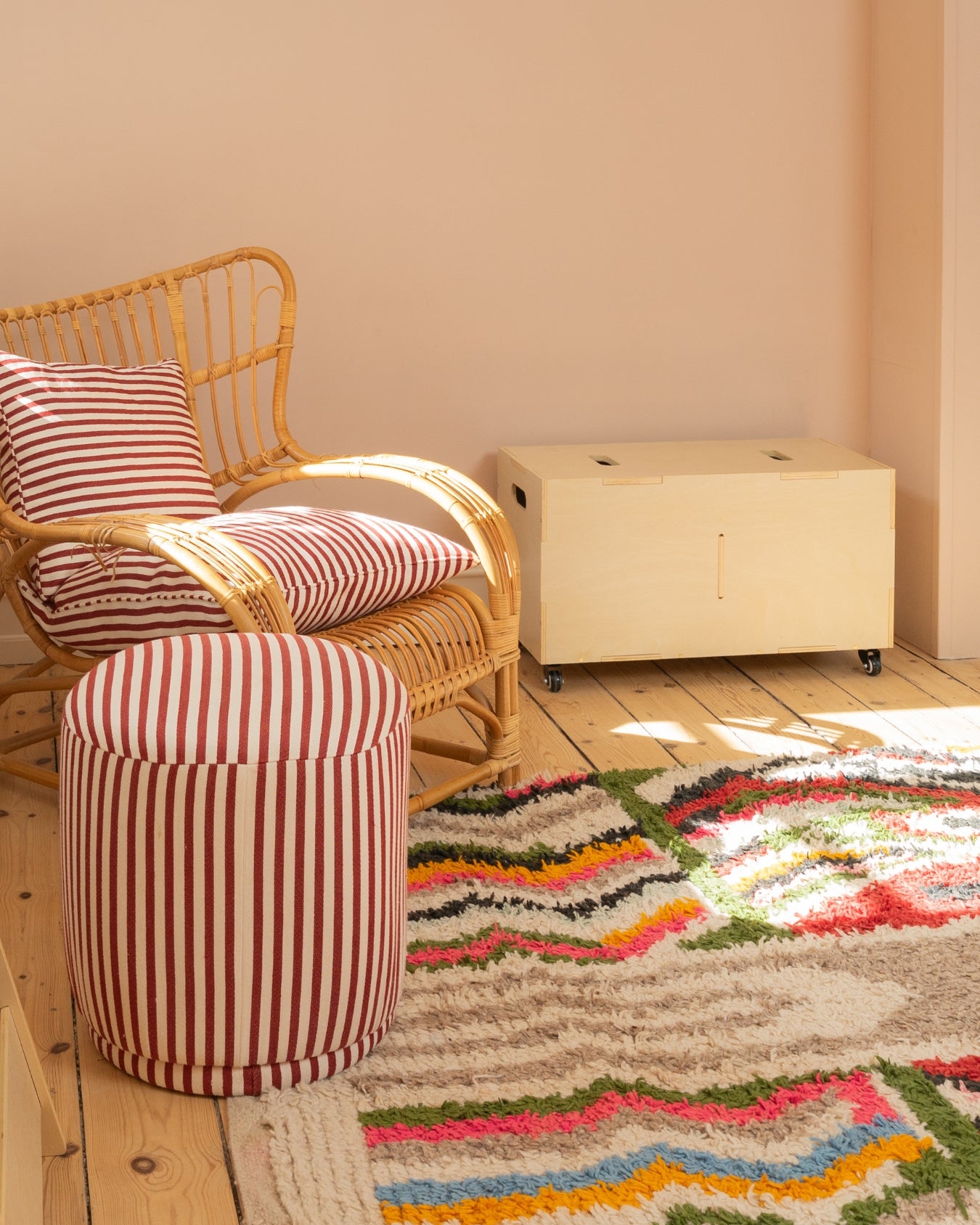 Wicker chair with striped cushions and a matching ottoman on a colorful rug.