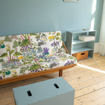Room with a colorful futon, small table, and storage box on wooden floor.