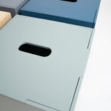 Three minimalist metal storage boxes with integrated handles, shown in gray, blue, and pale sage green on a clean white background.