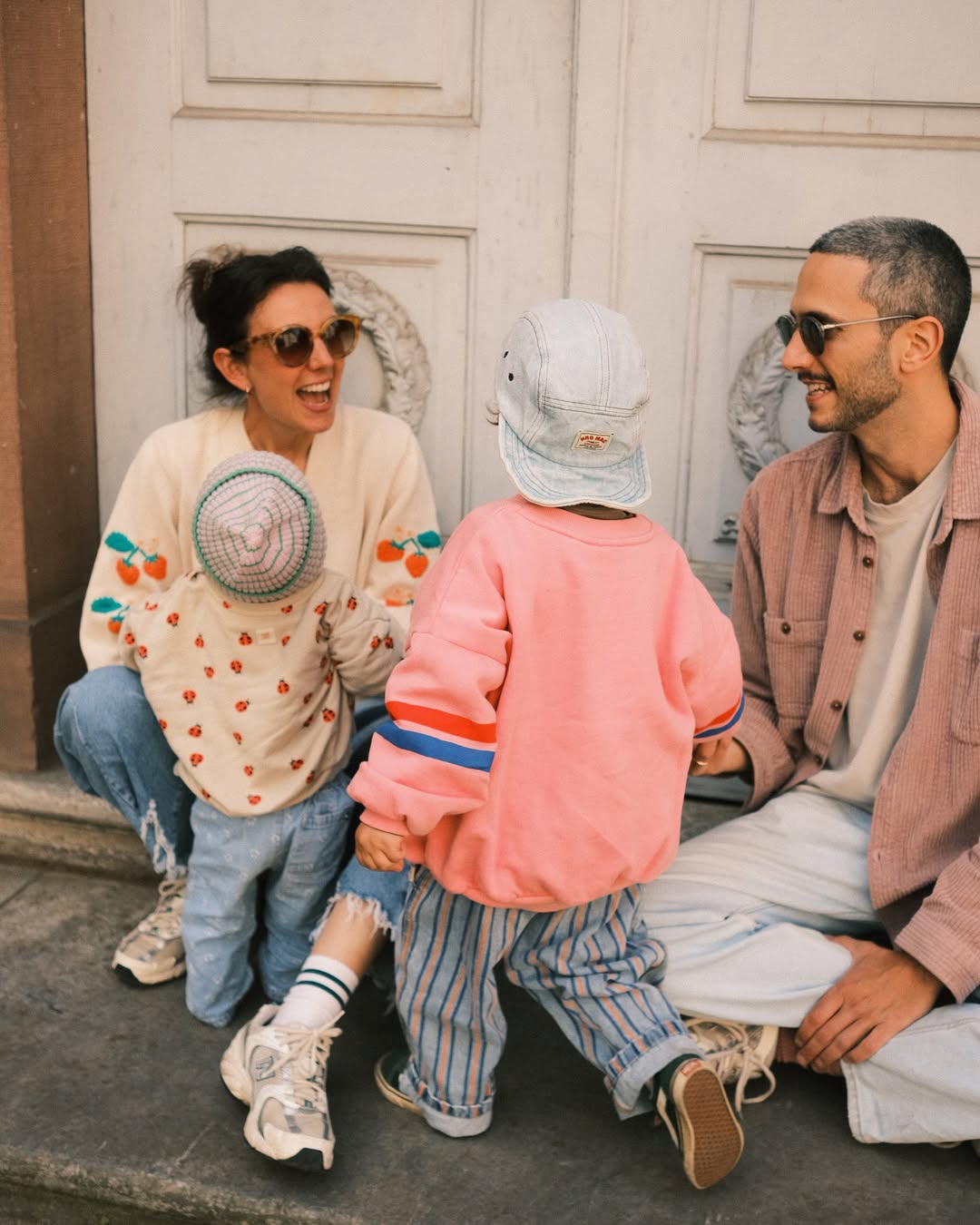 Family of three sitting on a step in an urban setting