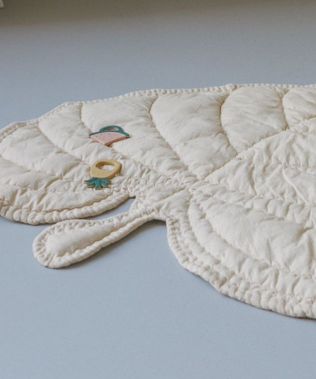 Quilted baby mat with animal shapes on a light gray background