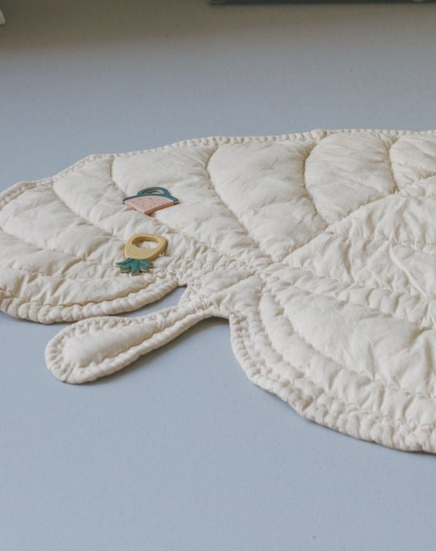 Quilted baby mat with animal shapes on a light gray background