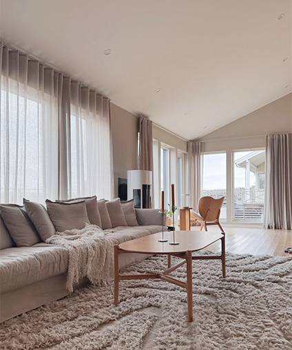 Modern living room with a sectional sofa, coffee table, and large windows.
