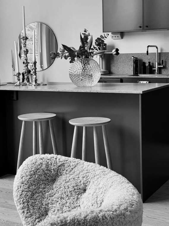 Modern kitchen with bar stools and a textured chair.