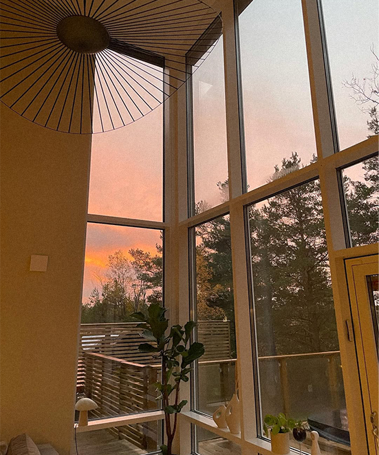 Sunset view from a room with large windows and a decorative umbrella.