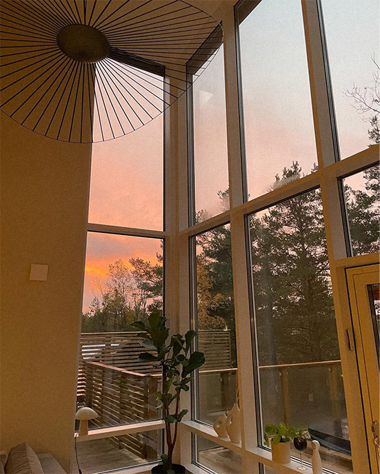 Sunset view from a room with large windows and a decorative umbrella.