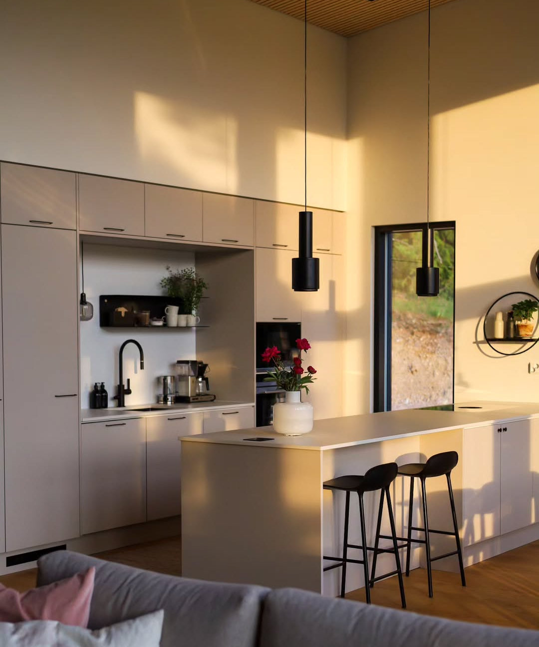 Modern kitchen with island and bar stools, featuring a cozy living area.