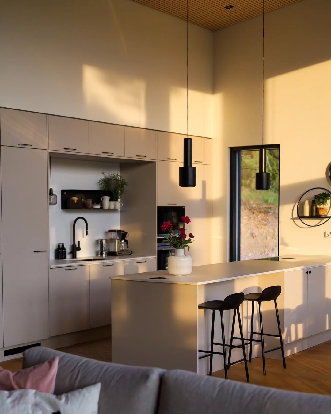Modern kitchen with island and bar stools, featuring a cozy living area.