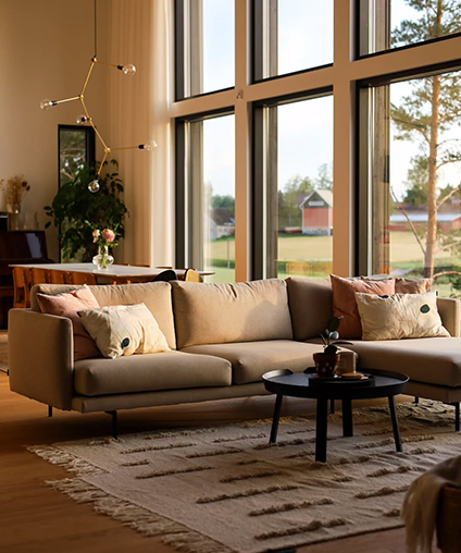 Modern living room with a beige sectional sofa, coffee table, and large windows.