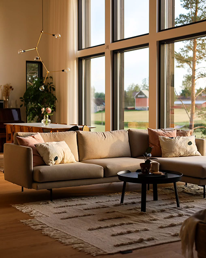 Modern living room with a beige sectional sofa, coffee table, and large windows.