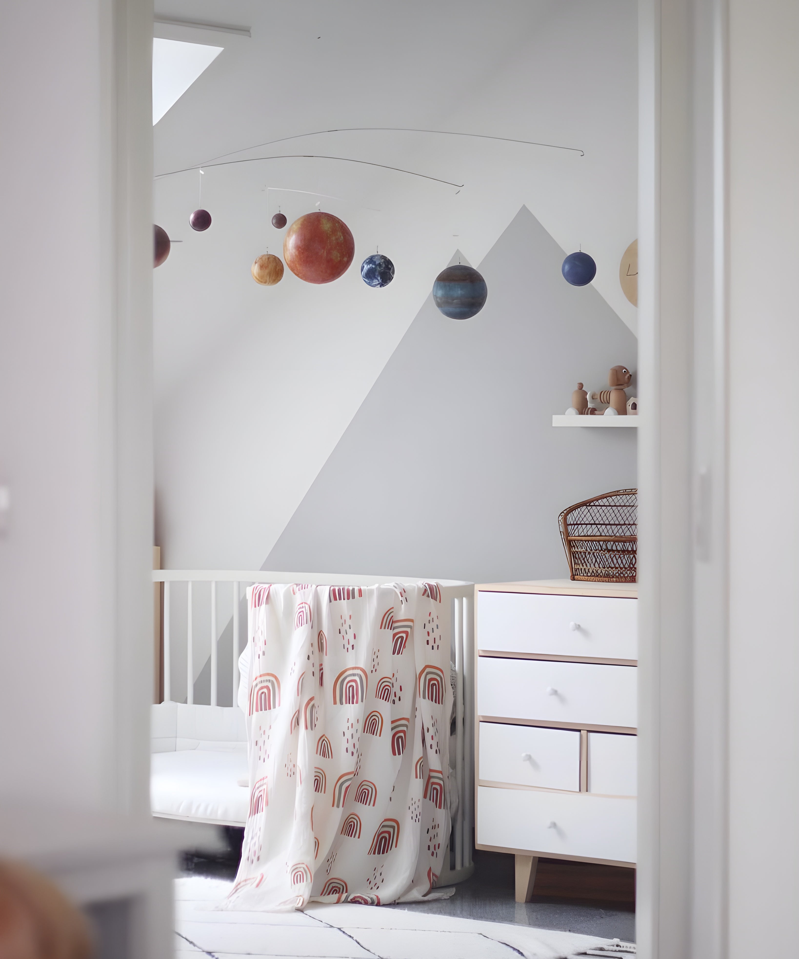 Nursery room with a crib, dresser, and wall with planet decorations.