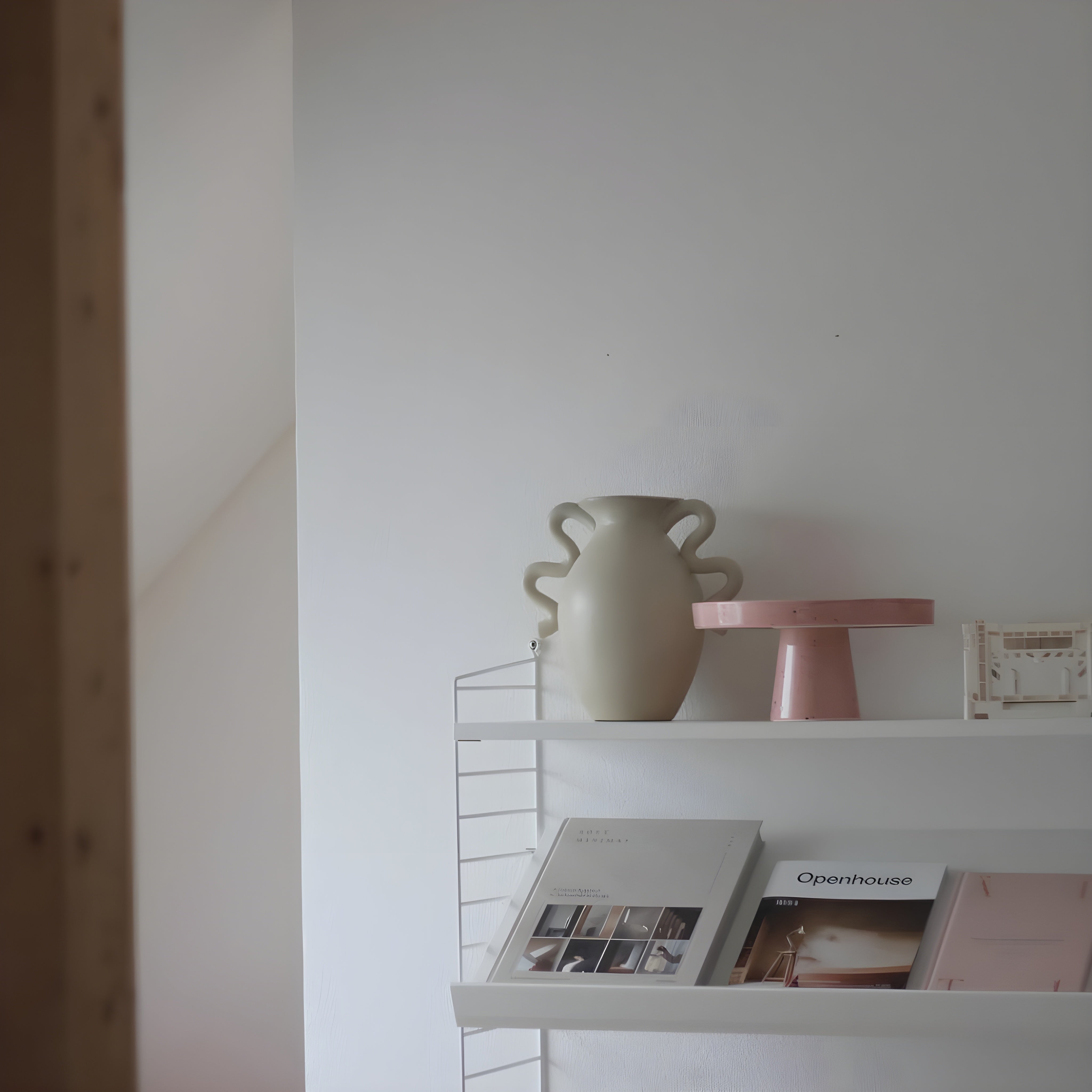 White shelf with a vase and books against a white wall