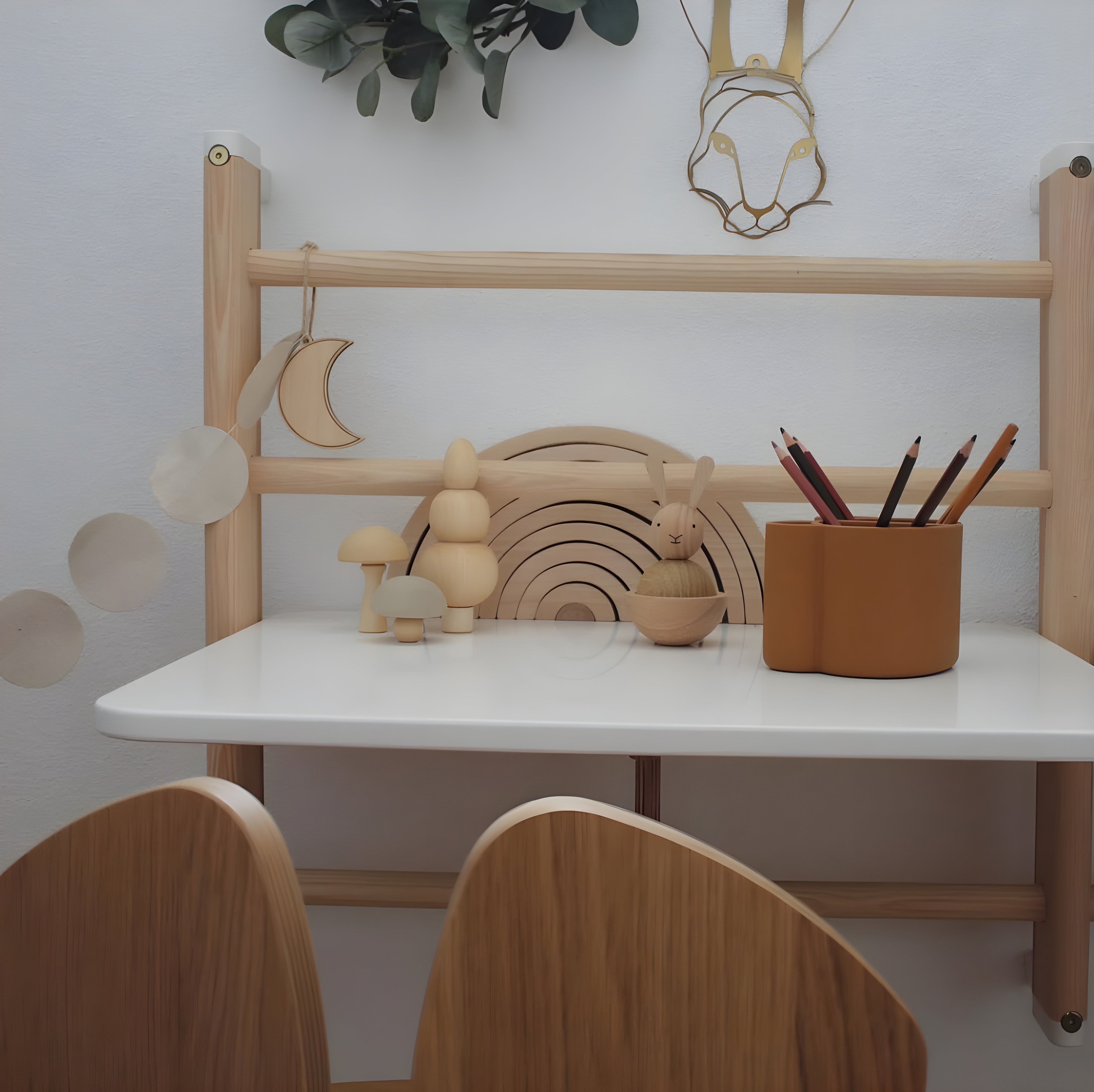 Children's play area with wooden furniture, toys, and decor on a white wall background.