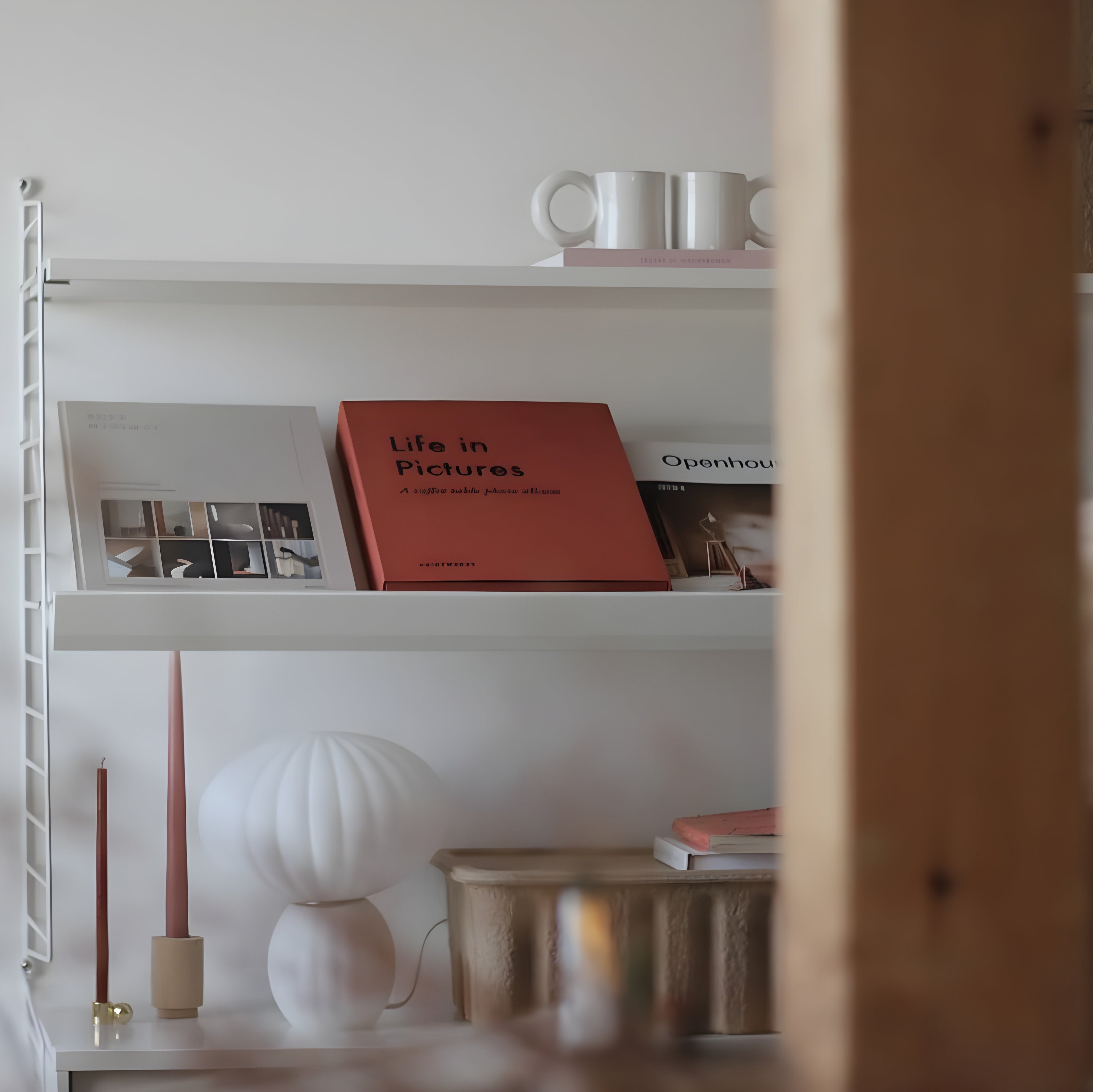 White bookshelf with books and decor items against a white wall.