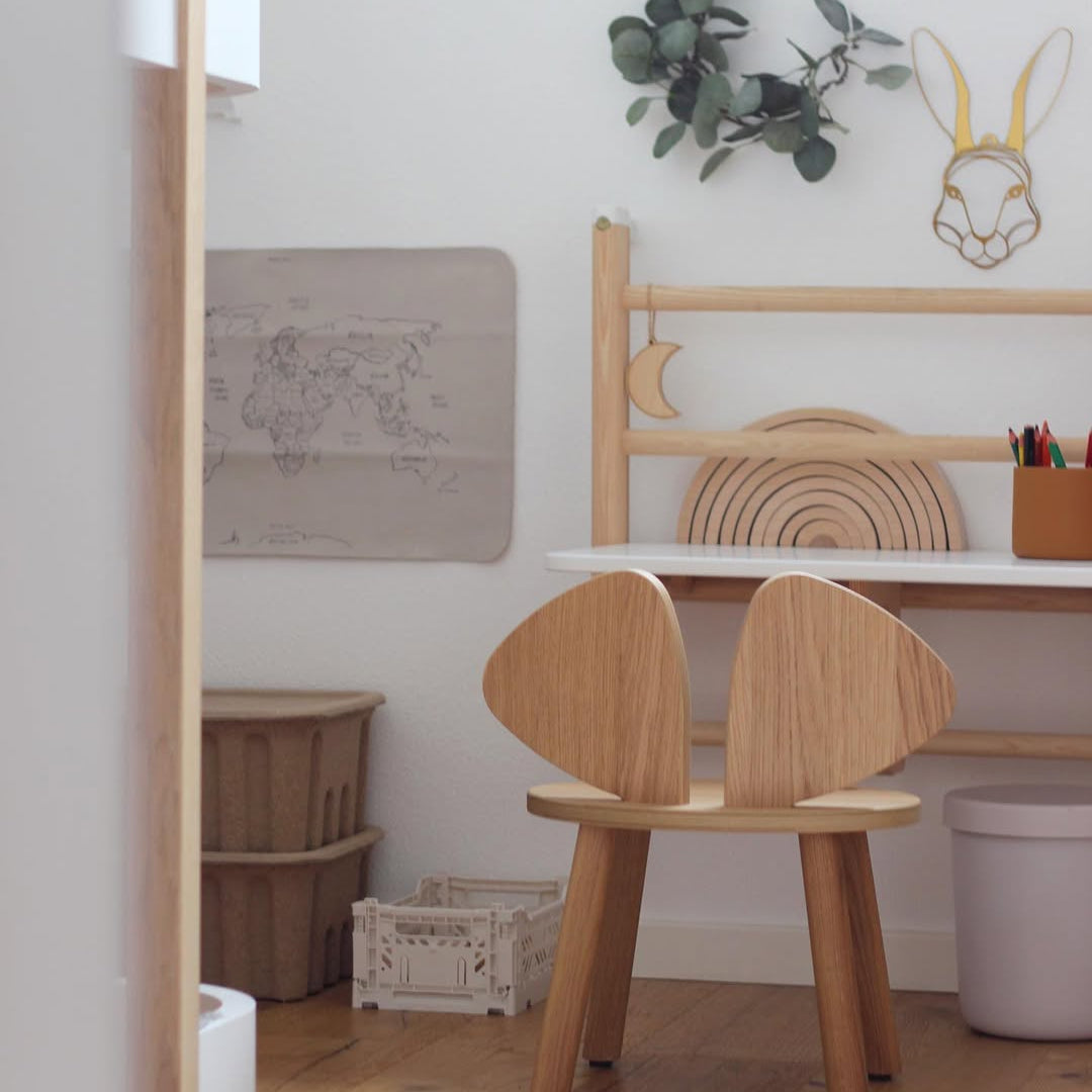 Wooden chair with rabbit ears in a child's room with a world map and plant decor.