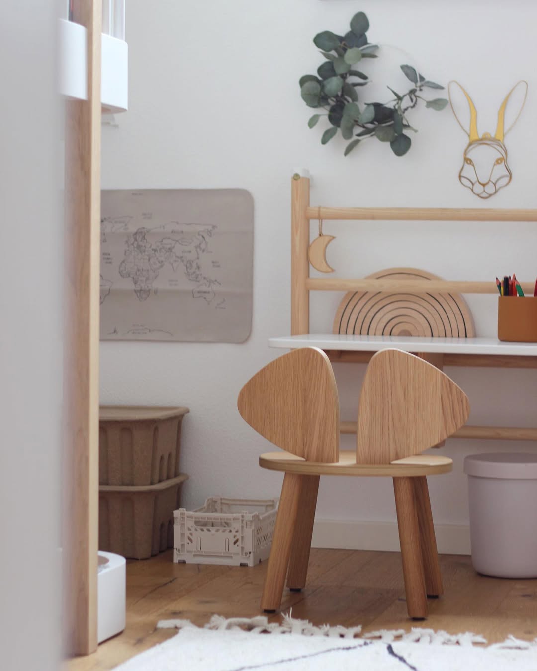 Wooden chair with rabbit ears in a child's room with a world map and plant decor.