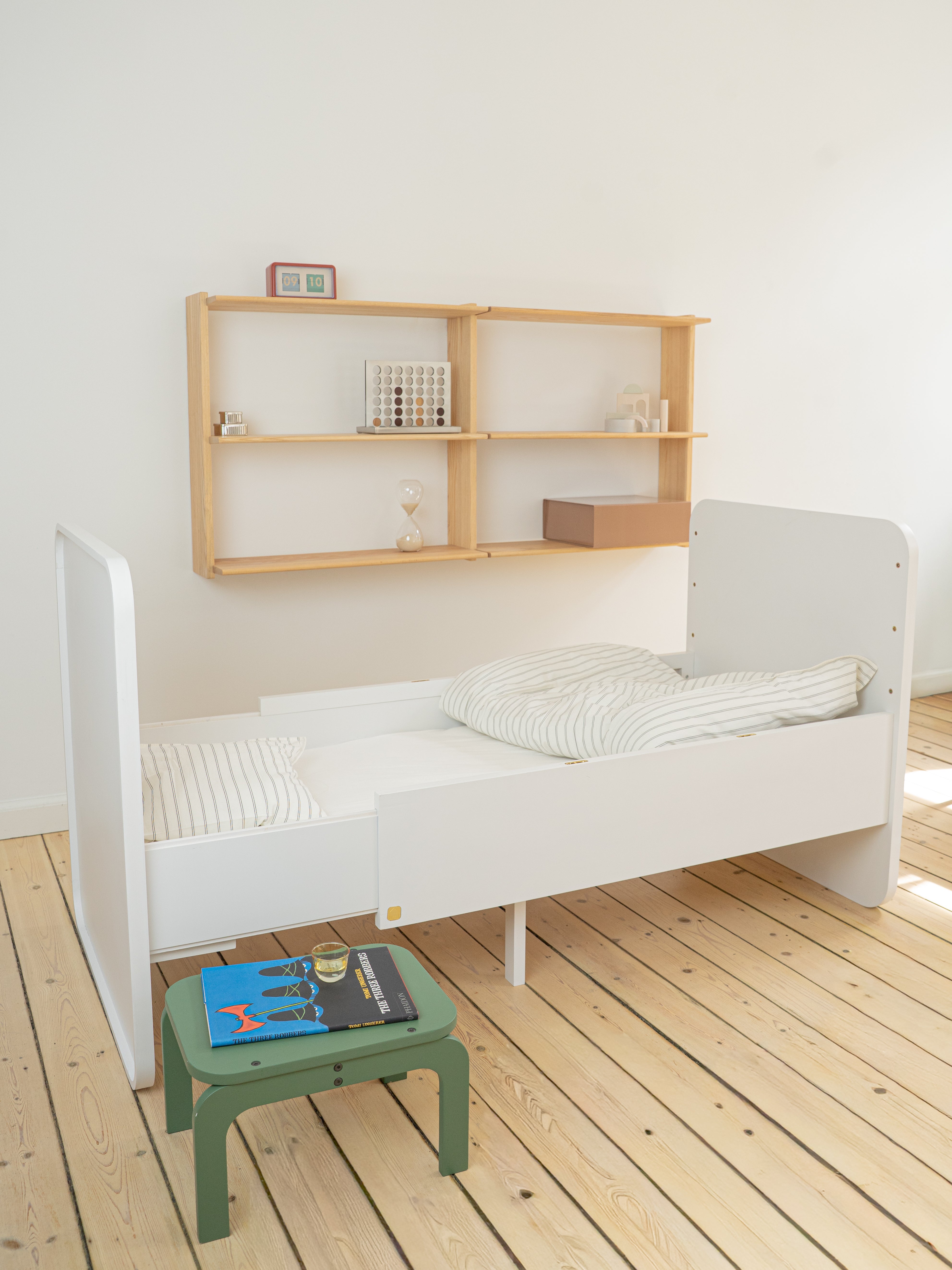 White crib with wooden shelves in a minimalistic room