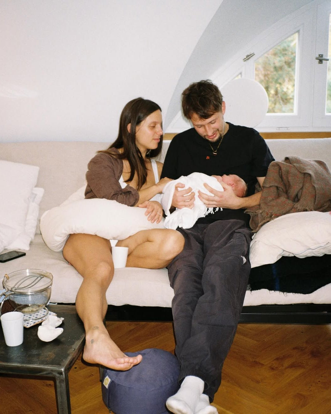 Newborn baby being held by a man and woman in a home setting.