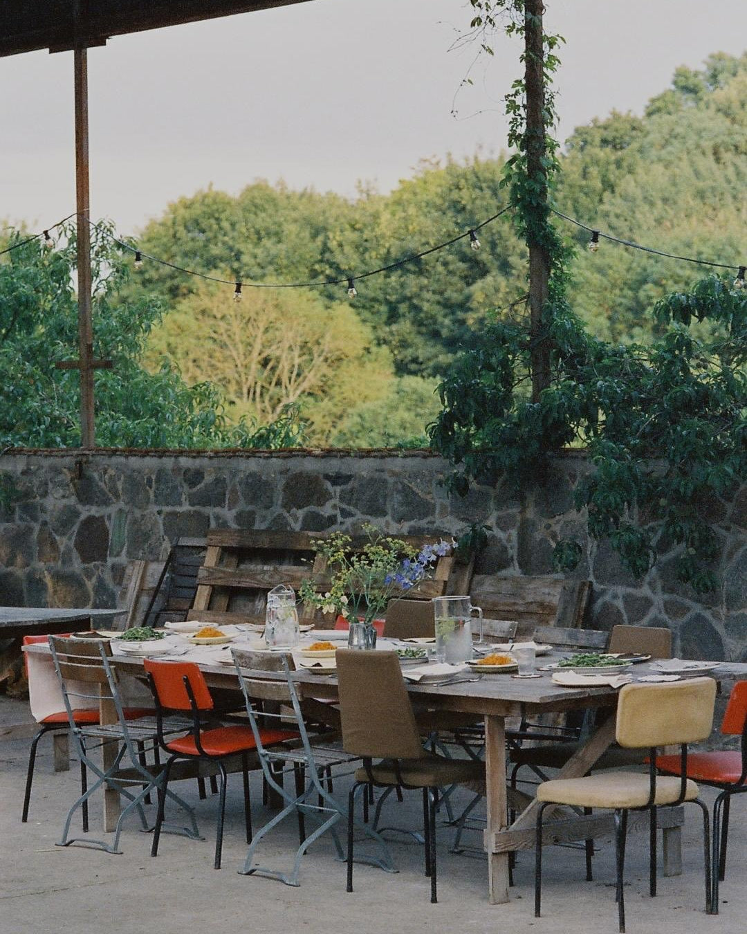 Outdoor dining area with a stone wall and greenery