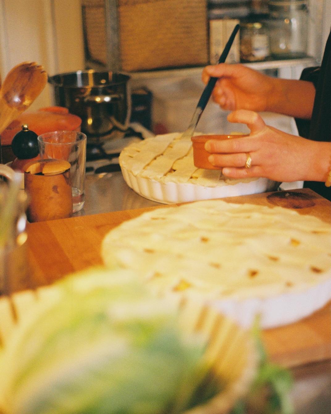 Person preparing a pie in a kitchen with various items on the counter.