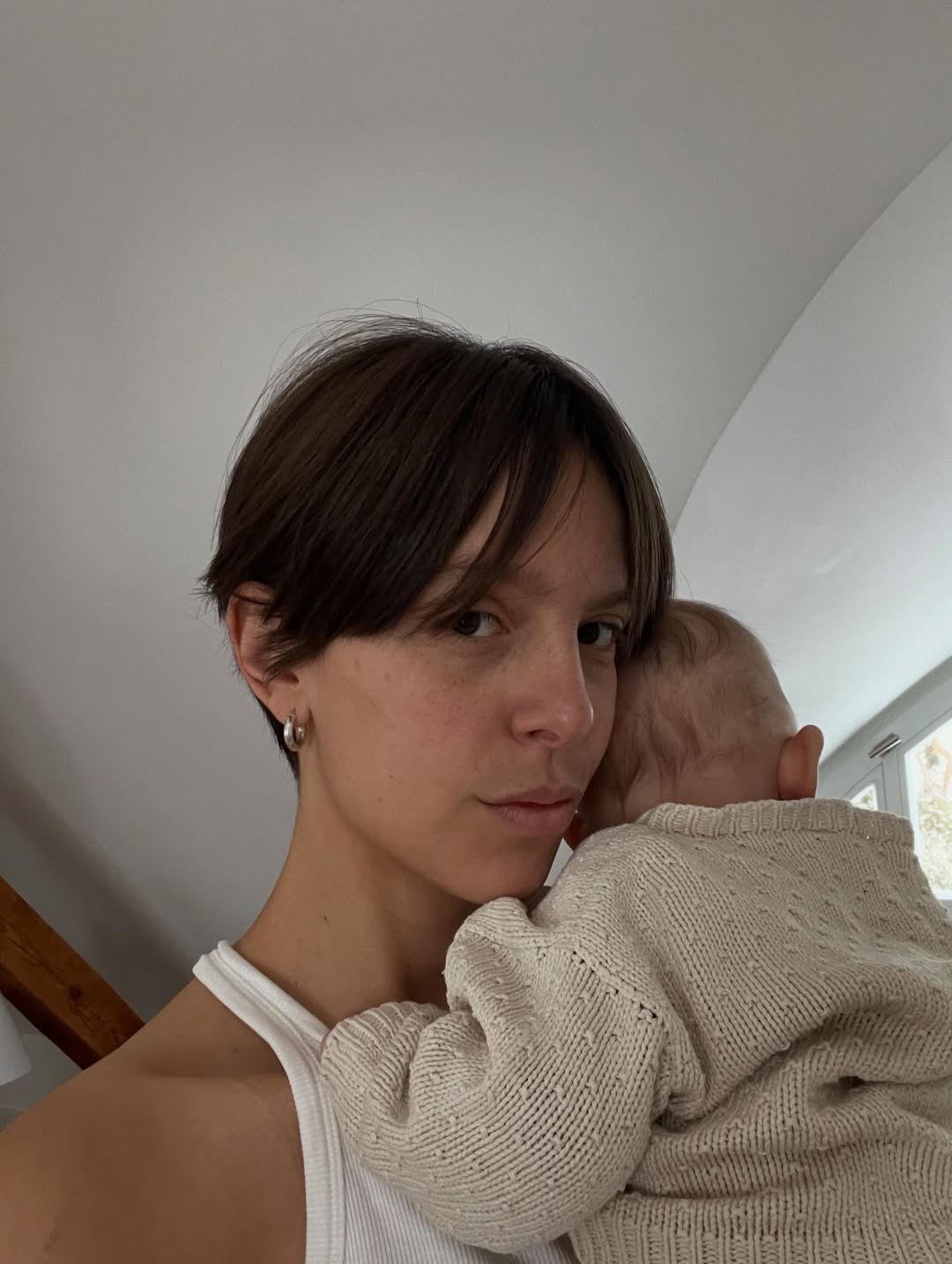 Woman holding a child close to her face indoors.