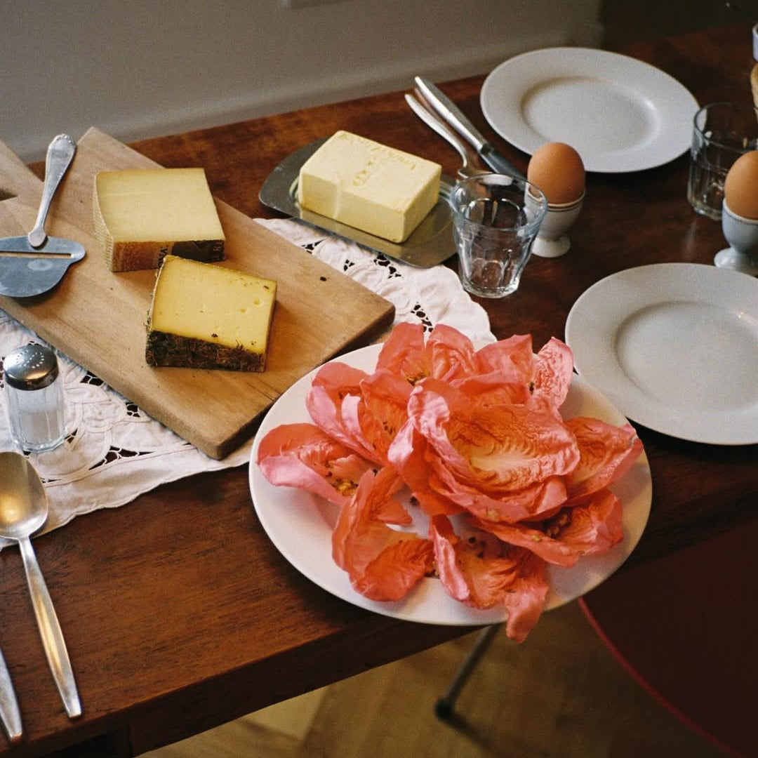 Table setting with cheese, tomatoes, and eggs on a wooden table.