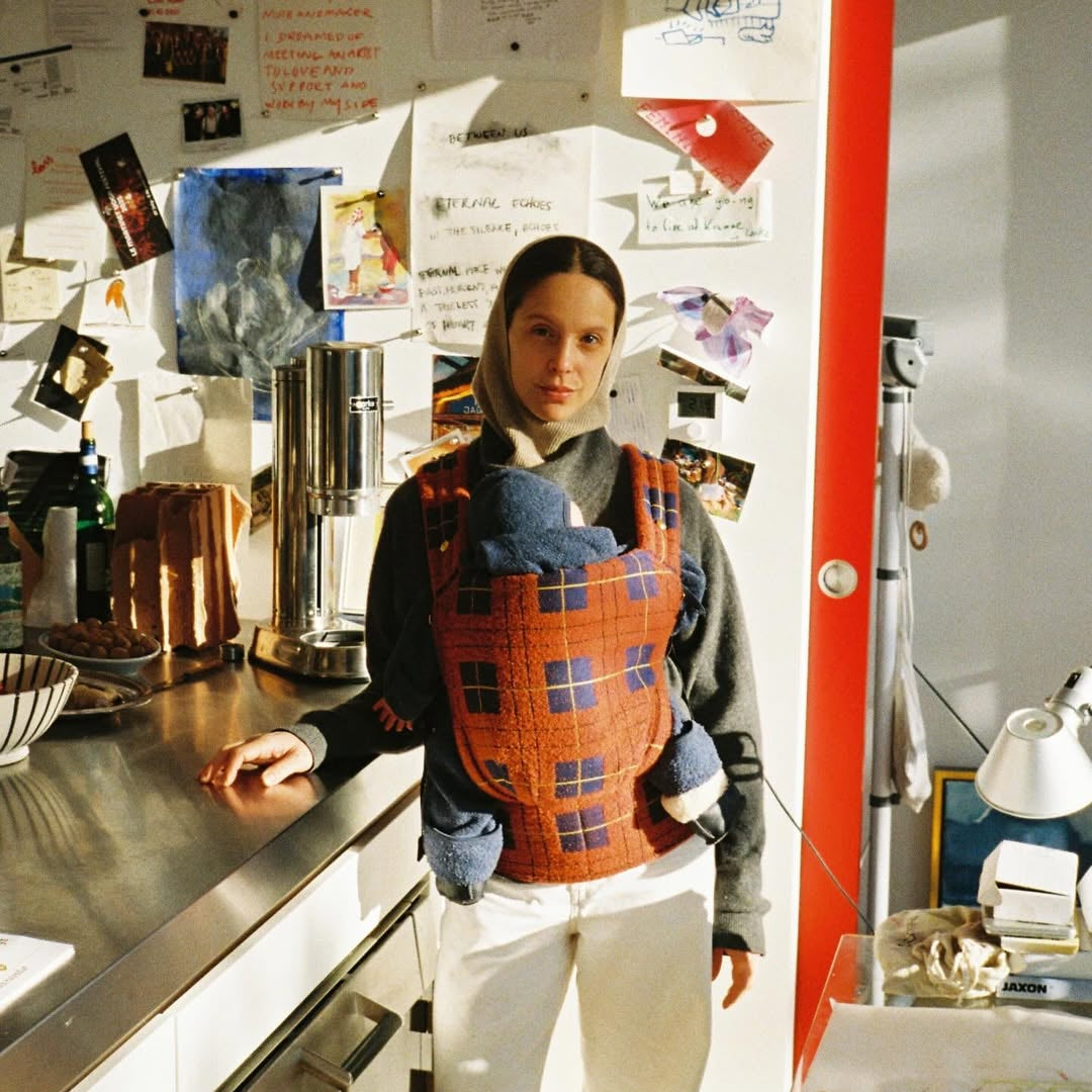 Person wearing a patterned apron in a kitchen setting with various items on the counter.