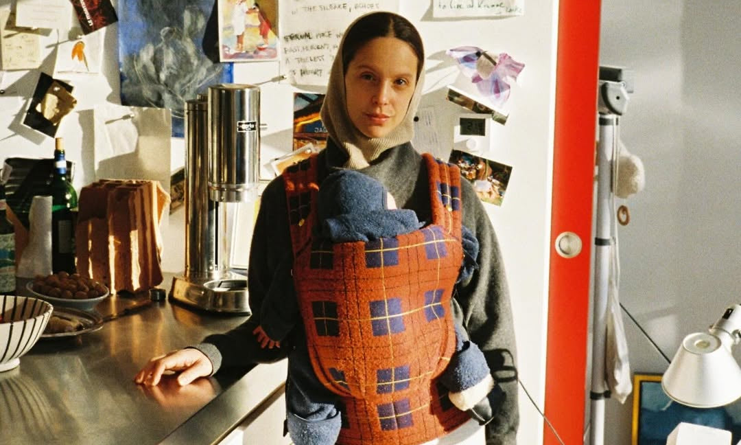 Person wearing a patterned apron in a kitchen setting with various items on the counter.