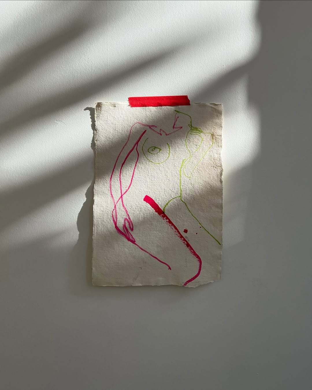 Hand-drawn figure on a piece of paper with red and green markers, placed against a light gray background.