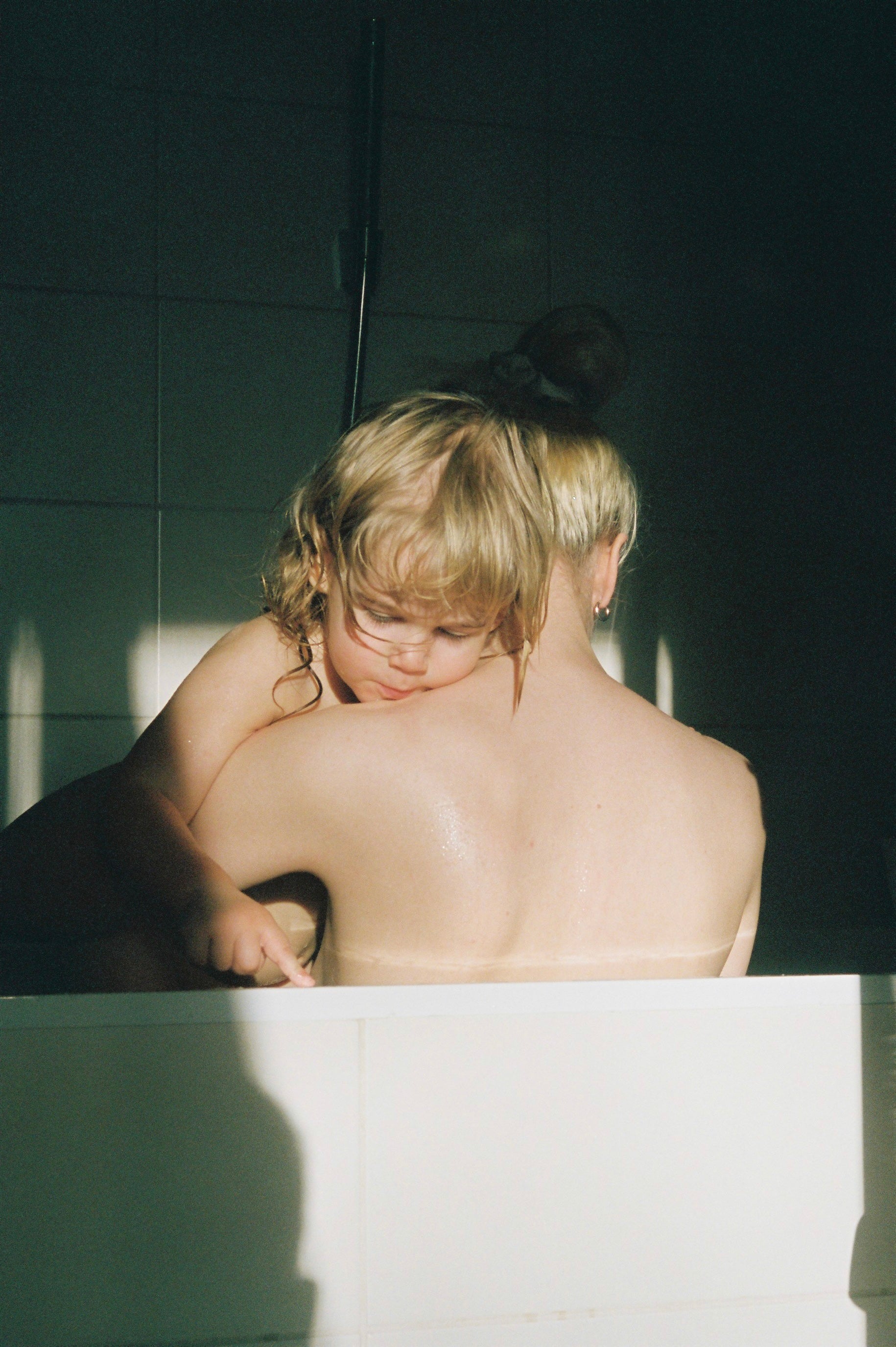 Two children in a bathtub with sunlight streaming in, creating a warm and intimate atmosphere.