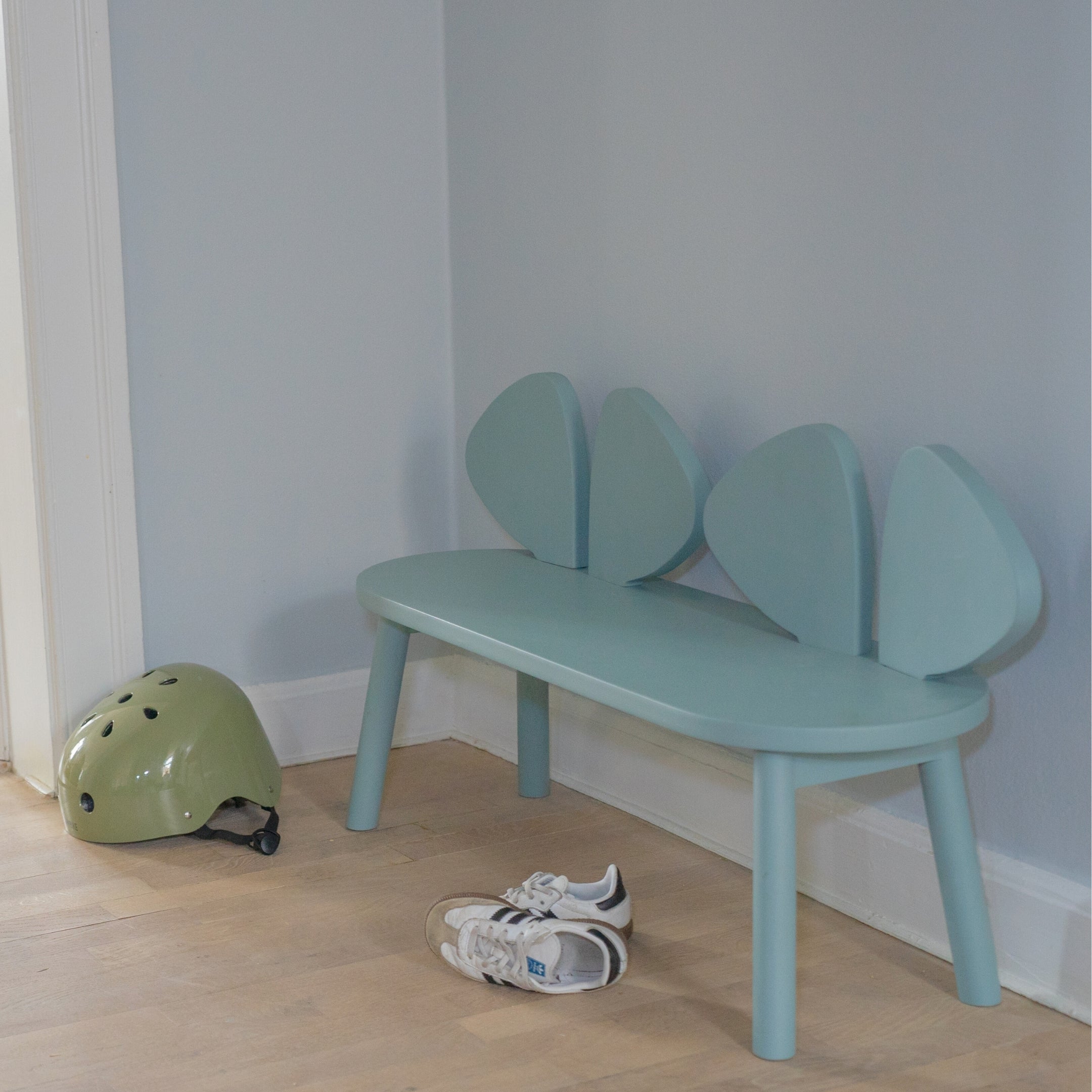 Children's bench with mouse design next to a helmet and shoes on a wooden floor.