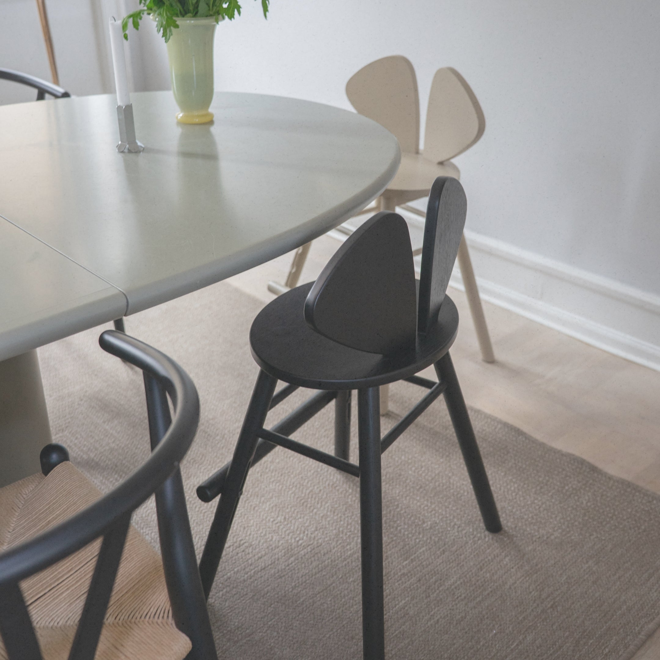Dining area with a round table and black chairs on a carpeted floor.
