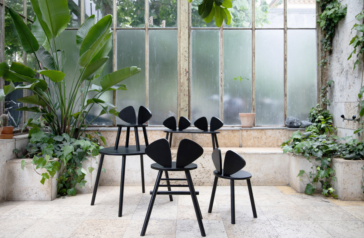 Black chairs in a room with large windows and potted plants