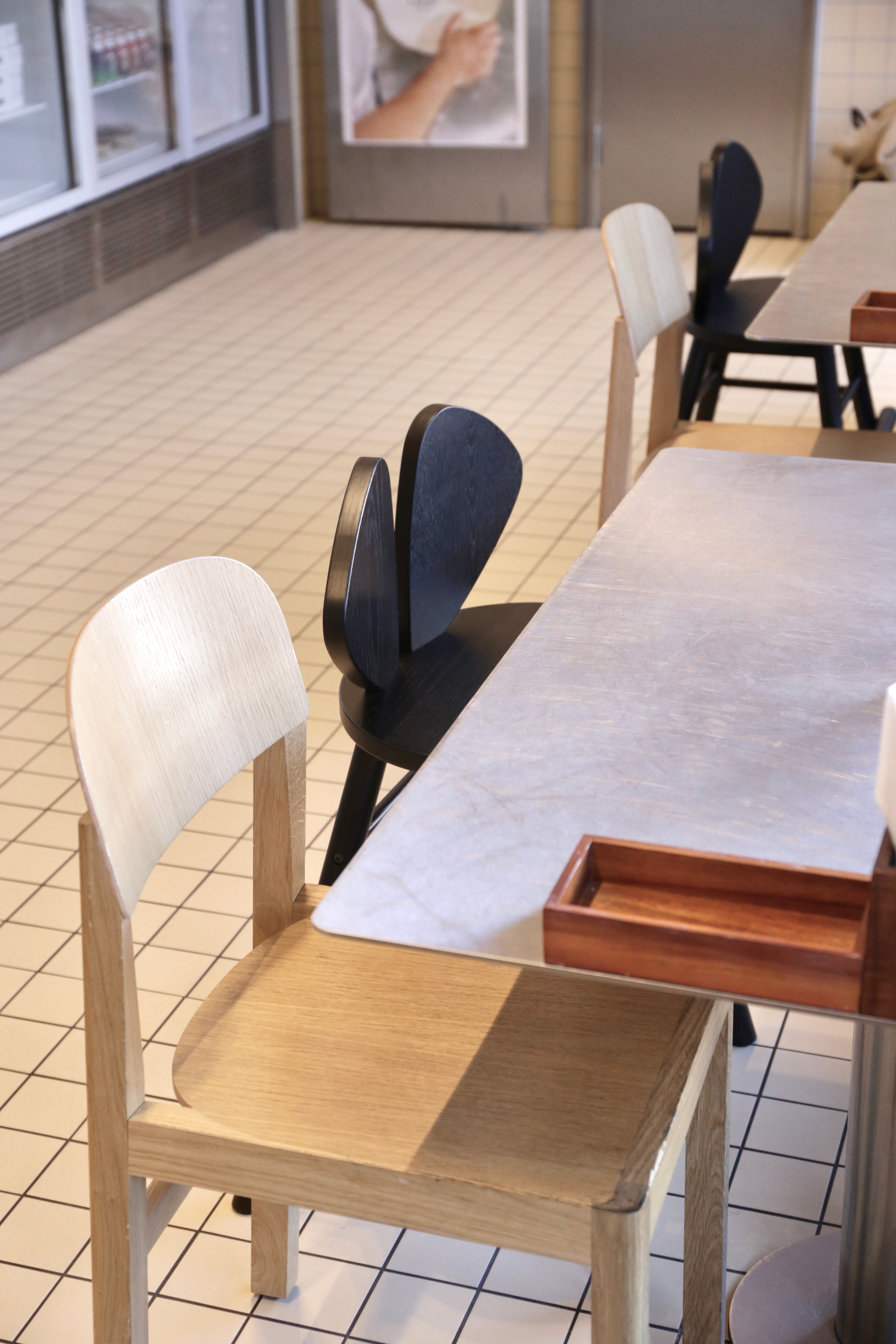 Dining area with wooden tables and chairs on a tiled floor.