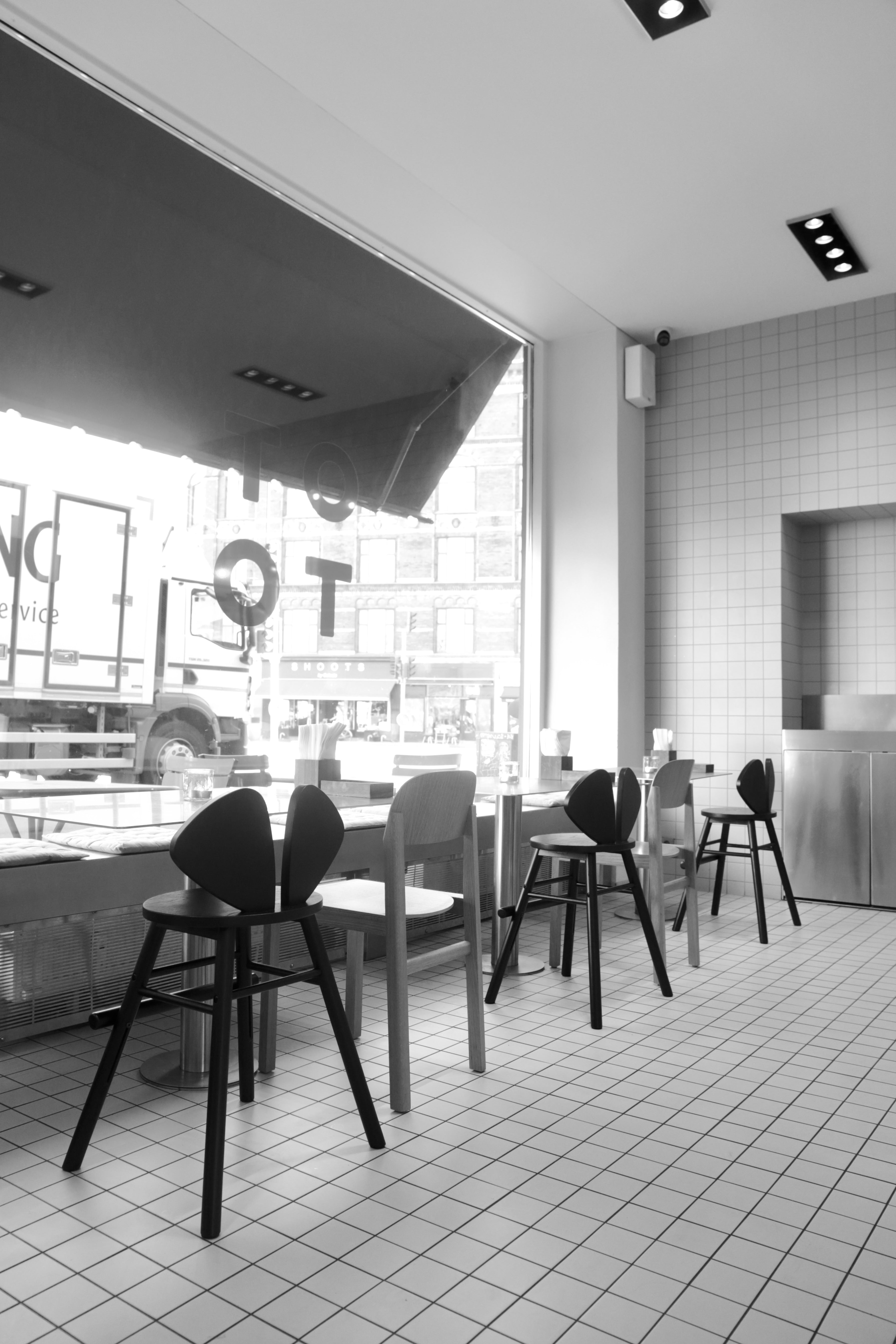 Modern cafe interior with tables, chairs, and large windows.
