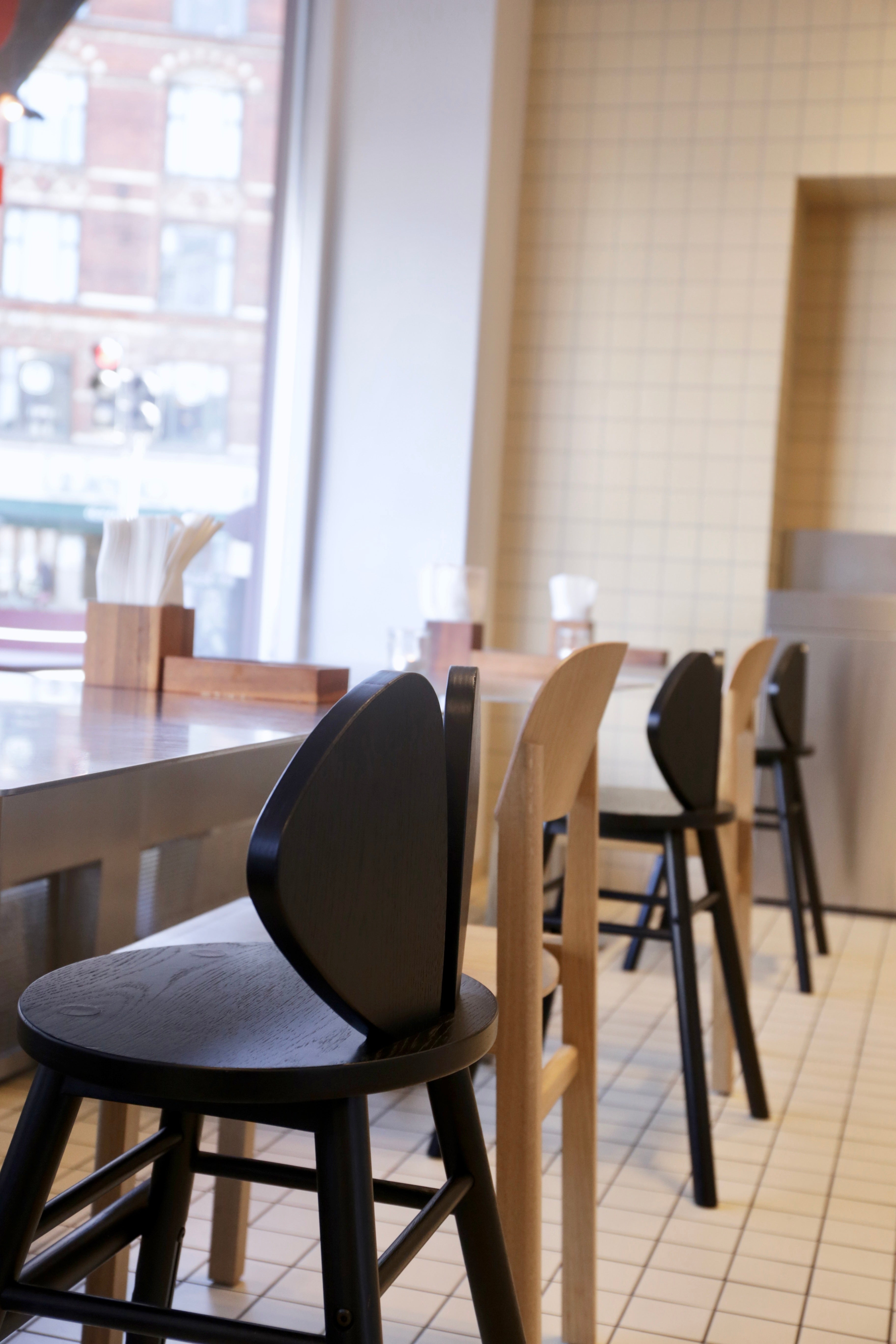 Dining area with black and beige chairs and tables in a tiled room.