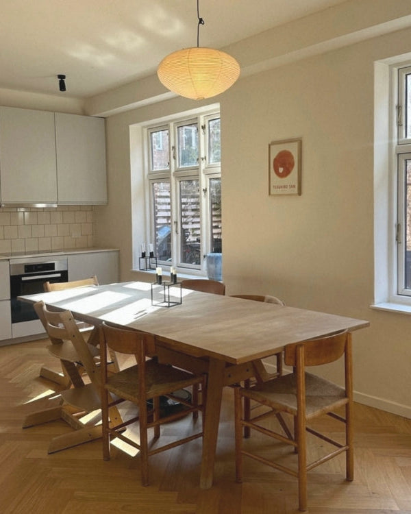 Dining area with wooden table and chairs in a well-lit room with large windows.